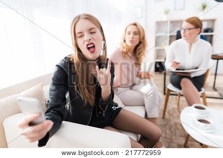 A teenage girl with her mother at a psychologist's reception. The girl has a complicated character. She does not listen to adults. She loves rock music and dressed in a leather jacket.