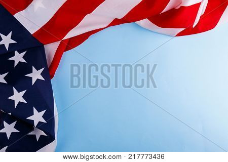 American flag the symbol of US independence lies unevenly along the perimeter of the left and the upper side on a blue background