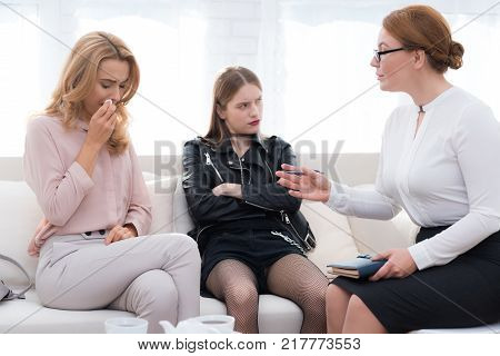 A teenage girl with her mother at a psychologist's reception. The girl has a complicated character. She does not listen to adults. She loves rock music and dressed in a leather jacket.
