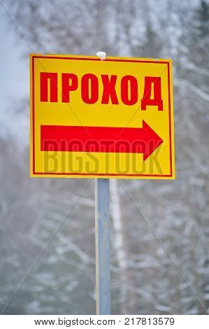 Yellow direction sign with red word and arrow on winter forest background on vertical shot