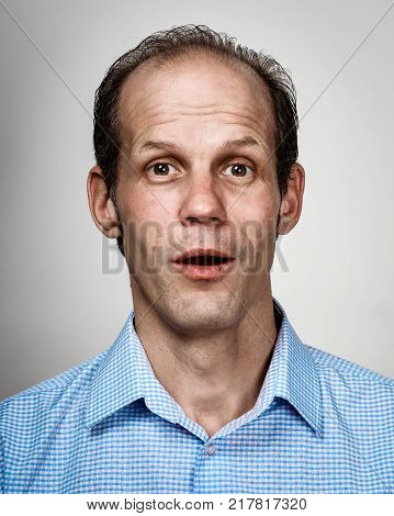 Portrait of surprised young business man on light gray background