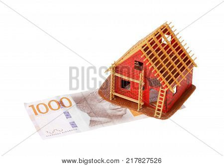 Stockholm Sweden - November 25 2017: The house under construction is built on a base of value illustrated by enb svenk banknote one thousand kronor isolated on white background.