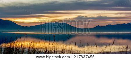 Panorama of the mountains and lake at sunrise with the sky reflection on the water