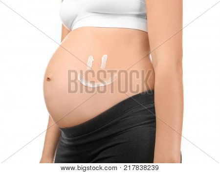 Smile painted with cream on pregnant woman's belly against white background, closeup