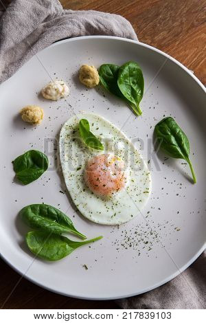 Single Fried Egg In Egg Shape Over White Plate Garnished With Spinach Green Herbs Salt Papper Horser