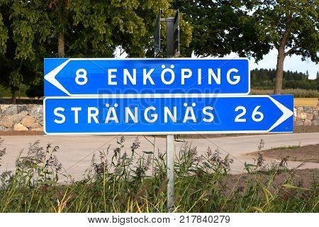 Swedish signpost with directional signs and distances to the two Swedish cities Enkoping and Vasteras..