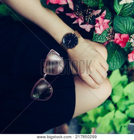 Female accessories concept. golden watch and black skirt.