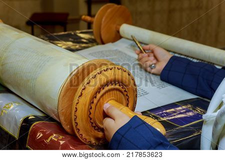 Reading a Torah scroll during a bar mitzvah ceremony with a traditional yad pointing towards the text on the parchment.
