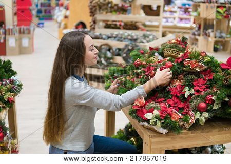Pretty customer woman choosing Christmas decorations. Various choice of New Year's wreath with decorations