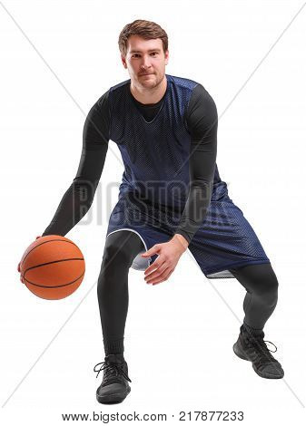 Basketball player, half-squat, in blue uniform, an athlete kneeling the ball throws the ball from one hand to the other, looks into the camera, isolated on a white background.