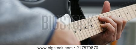 Male hands at home play and tune the electric guitar is engaged in music realizes listening enjoying music notation large concept closeup