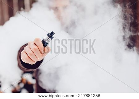 Vape. Man in the smoke holds an electronic device vape