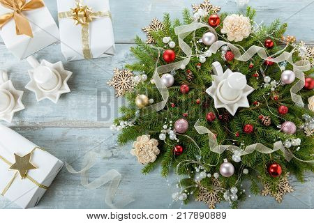 Decorated Advent wreath with white candles and gift on blue wooden background useful as christmas decoration