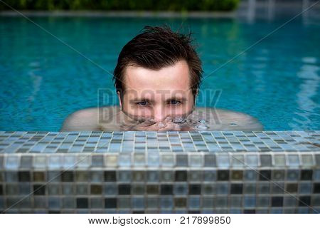 Young caucasian man swimming and lurking on summer vacation at pool.