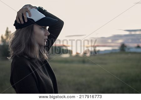portrait of girl in hat in profile at sunset and fields with tall grass