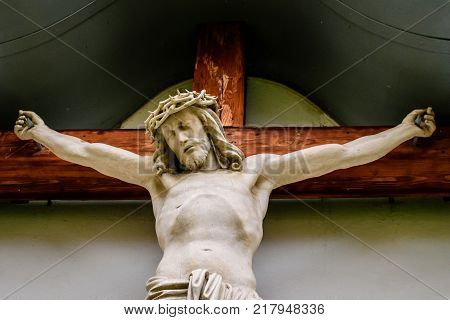a Jesus statue on a cross carved from wood and painted