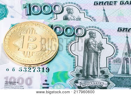 Golden bitcoin on the background of the russian ruble banknotes. Business concept of new virtual money