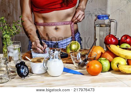 Young woman measures. Detox. Young girl measures the waist and uses proper nutrition. Concept: healthy lifestyle.Detox drinks, ingredients, dumbbells.