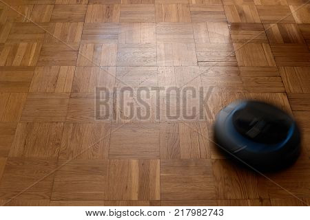 Robotic vacuum cleaner cleaning dust on laminate floor, natural movement, natural motion blur