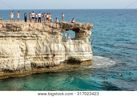 Protaras, Cyprus - June 25  2019: People Standing And Sitting On The Rocks, Enjoying The Crystal Cle