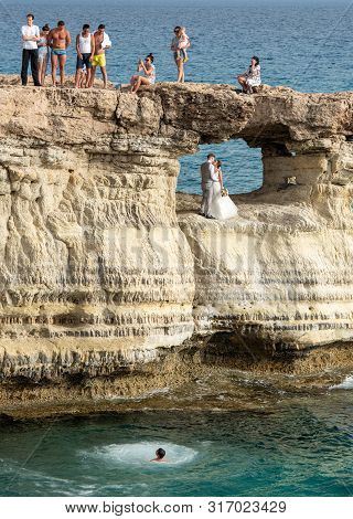 Protaras, Cyprus - June 25  2019: People Standing And Sitting On The Rocks, Enjoying The Crystal Cle