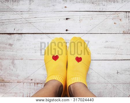 Selfie Feet Wearing Yellow Socks With Small Red Heart Shape On Wooden Floor Background. Love Self Co