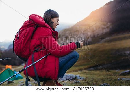 Woman Hiker With Smart Phone At Mountain Peak Cliff At The Sunset