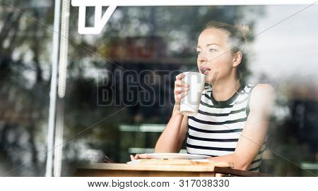Young Caucasian Woman Sitting Alone In Coffee Shop Thoughtfully Leaning On Her Hand, Looking Trough 