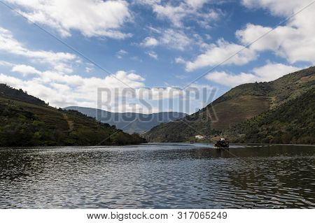 Scenic View Of The Douro River With A Traditional Rabelo Boat And Terraced Vineyards Near The Tua Vi