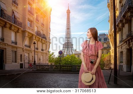 Asian Girl Walking In Small Paris Street With View On The Famous Paris Eiffel Tower On A Cloudy Rain
