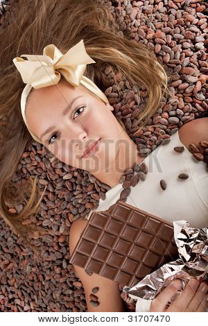 Smuk pige med chokolade på kakaobønner