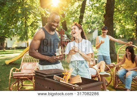 Group Of Happy Friends Having Beer And Barbecue Party At Sunny Day. Resting Together Outdoor In A Fo