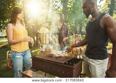 Group Of Happy Friends Having Beer And Barbecue Party At Sunny Day. Resting Together Outdoor In A Fo