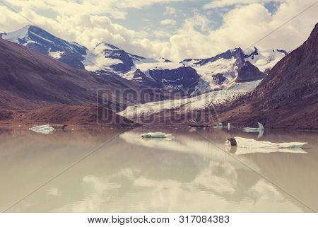 Serene scene by the mountain lake in Canada with reflection of the rocks in the calm water.