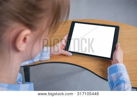 Woman Sitting At Wooden Table And Looking At Black Digital Tablet Computer Device With White Blank S