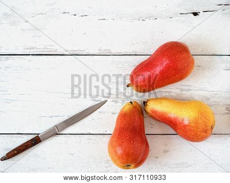 Three Ripe Red Pears Against A White Wooden Background. View From Above.