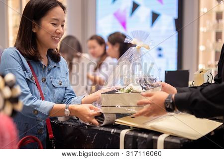 Happy Woman Customer Receiving Gift And Flower Boxset From Shop Manager.