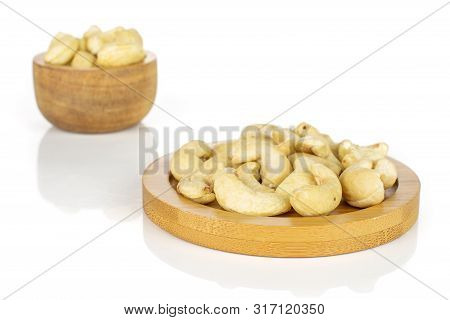 Lot Of Whole Unsalted Beige Cashew On Round Bamboo Coaster In Tiny Wooden Bowl Isolated On White Bac