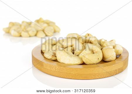 Lot Of Whole Unsalted Beige Cashew On Round Bamboo Coaster Isolated On White Background