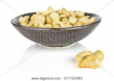 Lot Of Whole Unsalted Beige Cashew In Dark Ceramic Bowl Isolated On White Background