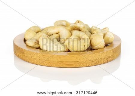 Lot Of Whole Unsalted Beige Cashew On Round Bamboo Coaster Isolated On White Background