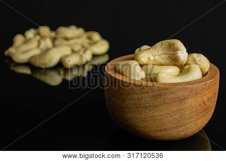 Lot Of Whole Unsalted Beige Cashew In Tiny Wooden Bowl Isolated On Black Glass