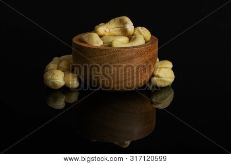 Lot Of Whole Unsalted Beige Cashew In Tiny Wooden Bowl Isolated On Black Glass