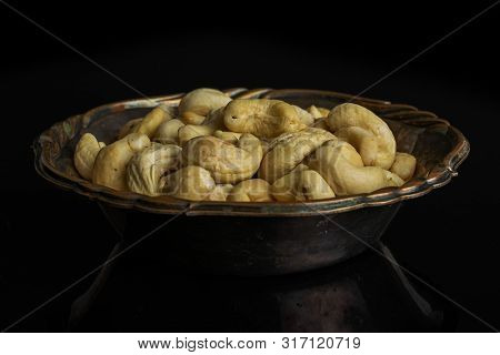 Lot Of Whole Unsalted Beige Cashew In Metal Bowl Isolated On Black Glass