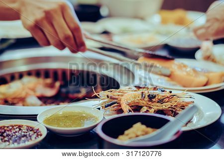 People Grilling Meat On A Smokeless Barbecue Grill In A Restaurant. Selective Focus On Shrimps.