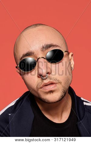 Studio Shot Of A Young Tattoed Bald Man Posing Against A Pink Background. 90s Style.