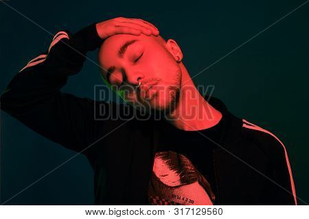Studio Shot Of A Young Tattoed Bald Man Posing Against A Colorful Background. 90s Style.