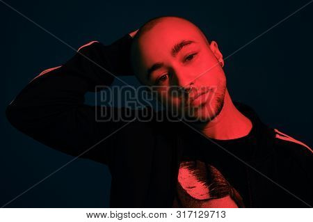 Studio Shot Of A Young Tattoed Bald Man Posing Against A Colorful Background. 90s Style.