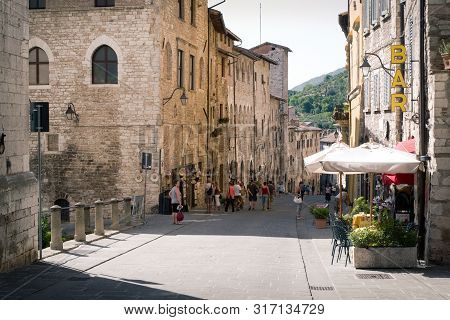Gubbio, Italy - 11 August, 2019: Tourists Visit A Street In The Umbrian City On A Hot Summer Day