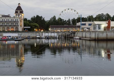 Beautiful Port City With Hotel And Ferris Wheel, Evening View From The Water.